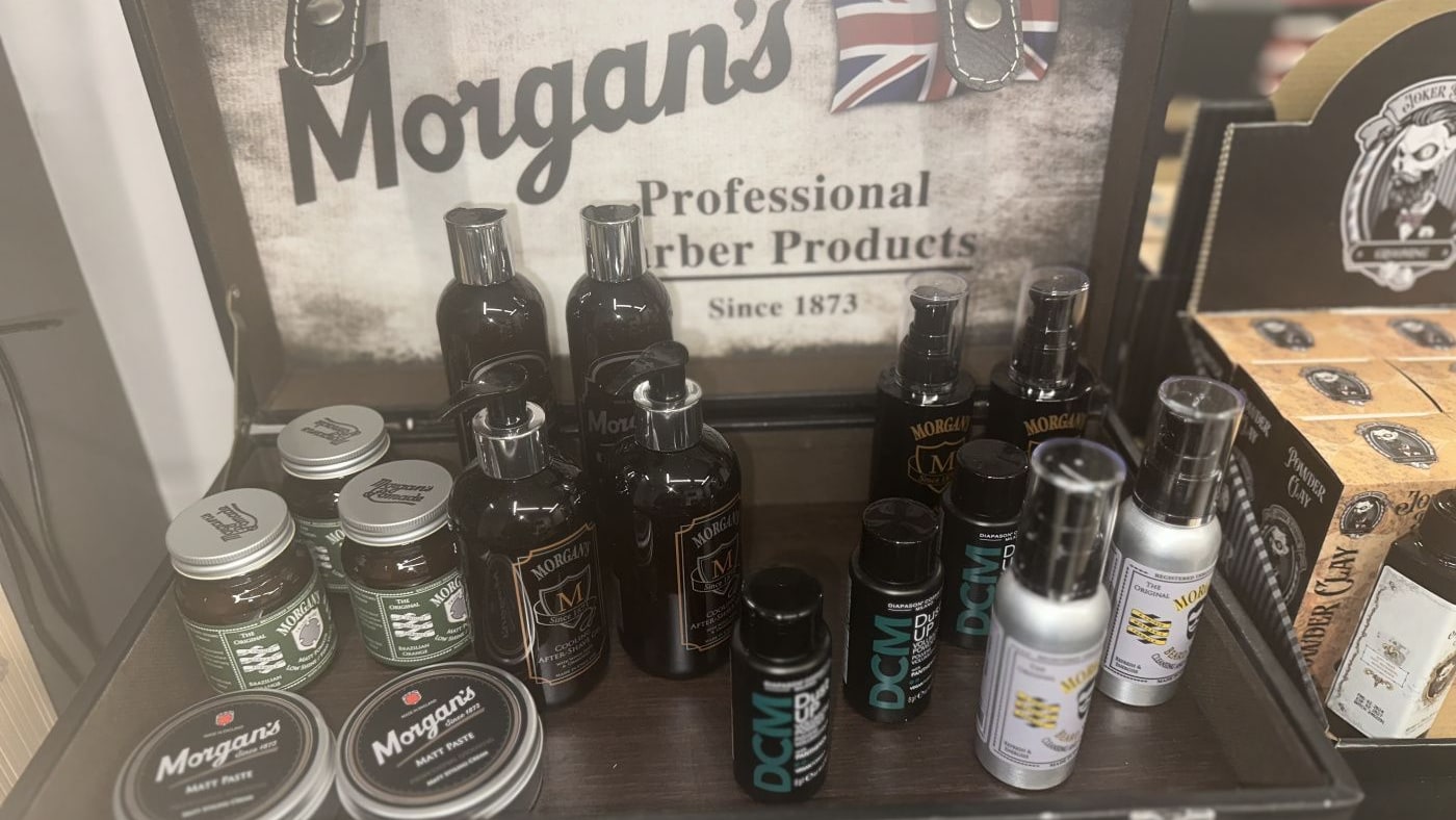 Η πρόσοψη του JOHNNY'S BARBERSHOP στην Ολύμπου 121, με το στρογγυλό σήμα στη τζαμαρία και την κόκκινη, λευκή και μπλε κολόνα barber
